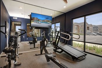 a gym with exercise equipment and a tv on the wall  at Watermark on Twenty Mile, Parker, Colorado